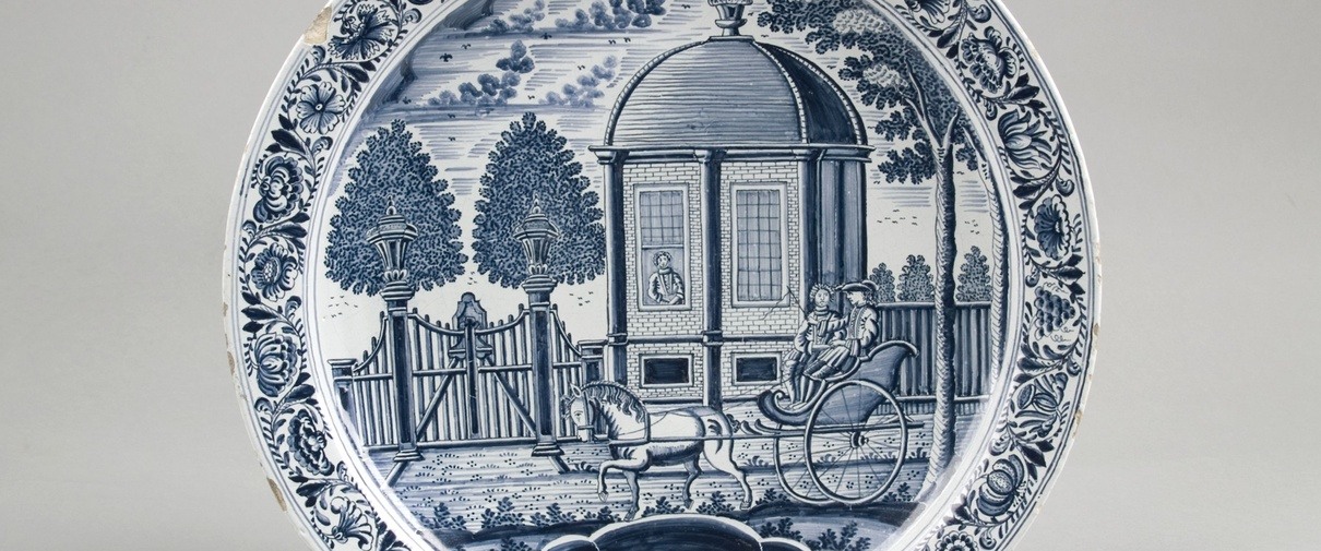 Schotel met stel in sjees voor een theekoepel, 1780, Gleibakkerij Buiten de Kerkpoort, Harlingen, schilder Jan Eelkes Kronenburg, aardewerk, Keramiekmuseum Princessehof (bruikleen Ottema-Kingma Stichting) . Klik op de afbeelding om te vergroten.​