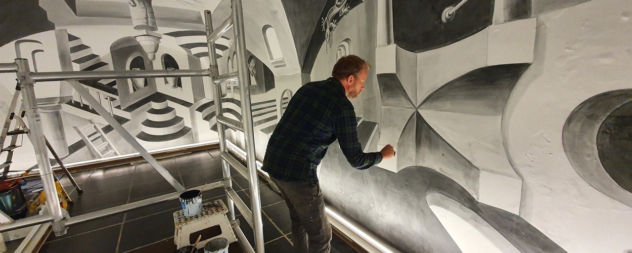 Leon Keer aan het werk aan de muurschildering in de expositie 'Thuis bij M.C. Escher.'