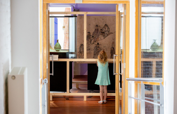 Meisje in groen jurkje kijkt naar de voorwerpen in de tentoonstelling. Foto door Ruben van Vliet