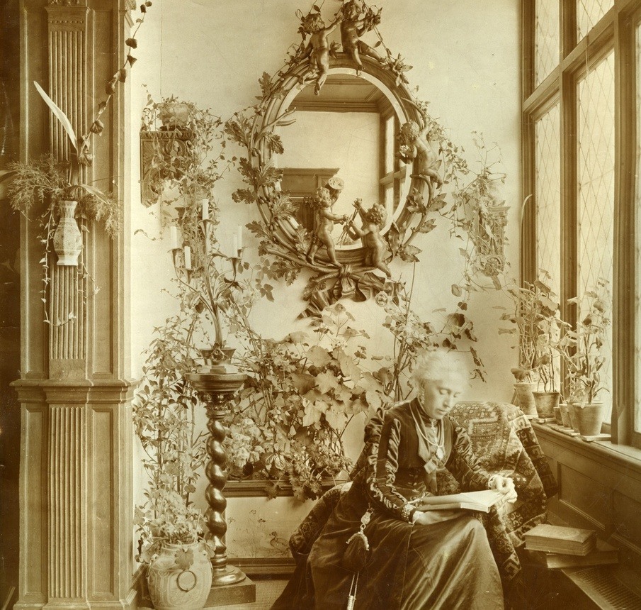 3: Kate Bisschop-Swift lezend in de serre van villa Frisia, 1894-1904. Fries Museum. Achter Kate hangt de spiegel die ze van Elisabeth cadeau kreeg.