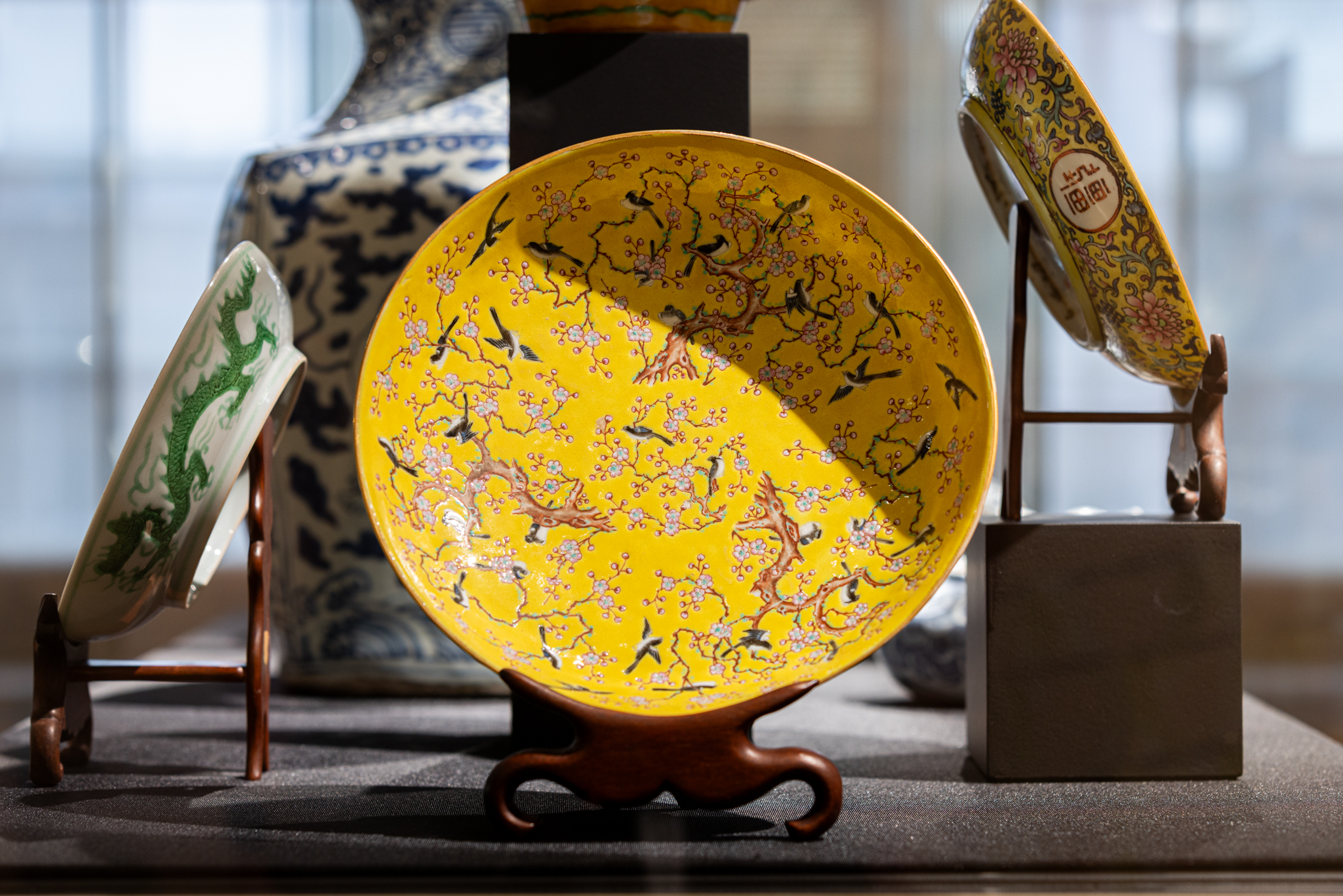 De kleuren van de eksters op dit bord contrasteren mooi met het heldere geel en het zachte roze van de bloesem. Sinds de Song-dynastie (960-1279) werden bloemen en vogels veelvuldig afgebeeld op Chinese painteringen. Eksters staan in China symbool voor voorspoed. Ze komen dan ook veel voor als decor op Chinees porselein, vooral in de Qing-dynastie (1644-1911). Bord met decor van eksters en prunus. China, Qing, Tongzhi (1862 – 1874), porseleinfamille, rose.